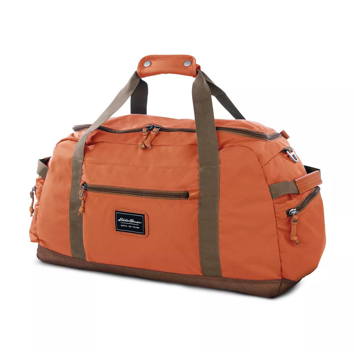 The Eddie Bauer Bygone Recycled 45L Duffel in Terracotta, made from recycled nylon, boasts an orange color with brown straps and multiple zip compartments. A rectangular label accents the front against a white background.