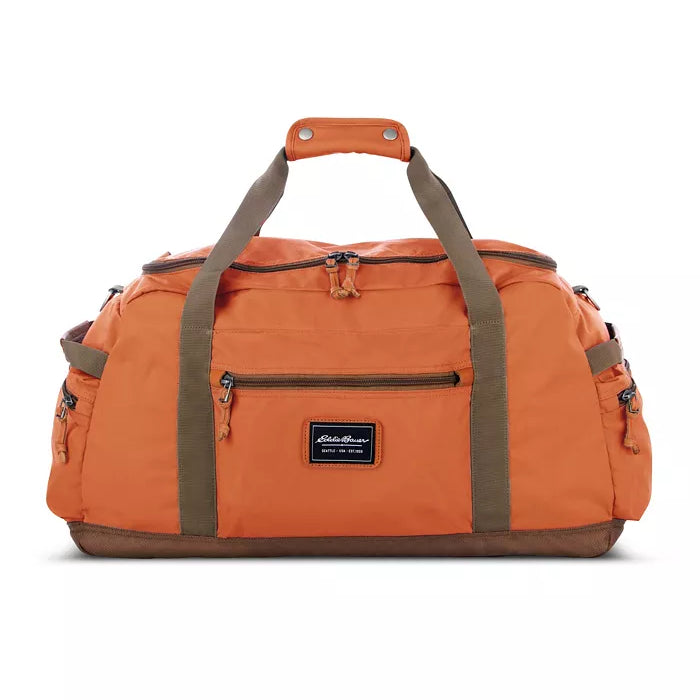 The Eddie Bauer Bygone Recycled 45L Duffel in terracotta, made from recycled nylon, features brown handles and trim, multiple zippered pockets, and a durable design label on the front.