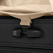 Close-up of a zipper pull on the textured fabric of a Briggs & Riley Baseline Essential 22 Carry-On Expandable Spinner. The pull attaches to the suitcases zipper, and a beige fabric tab seems part of the bags lining or flap.