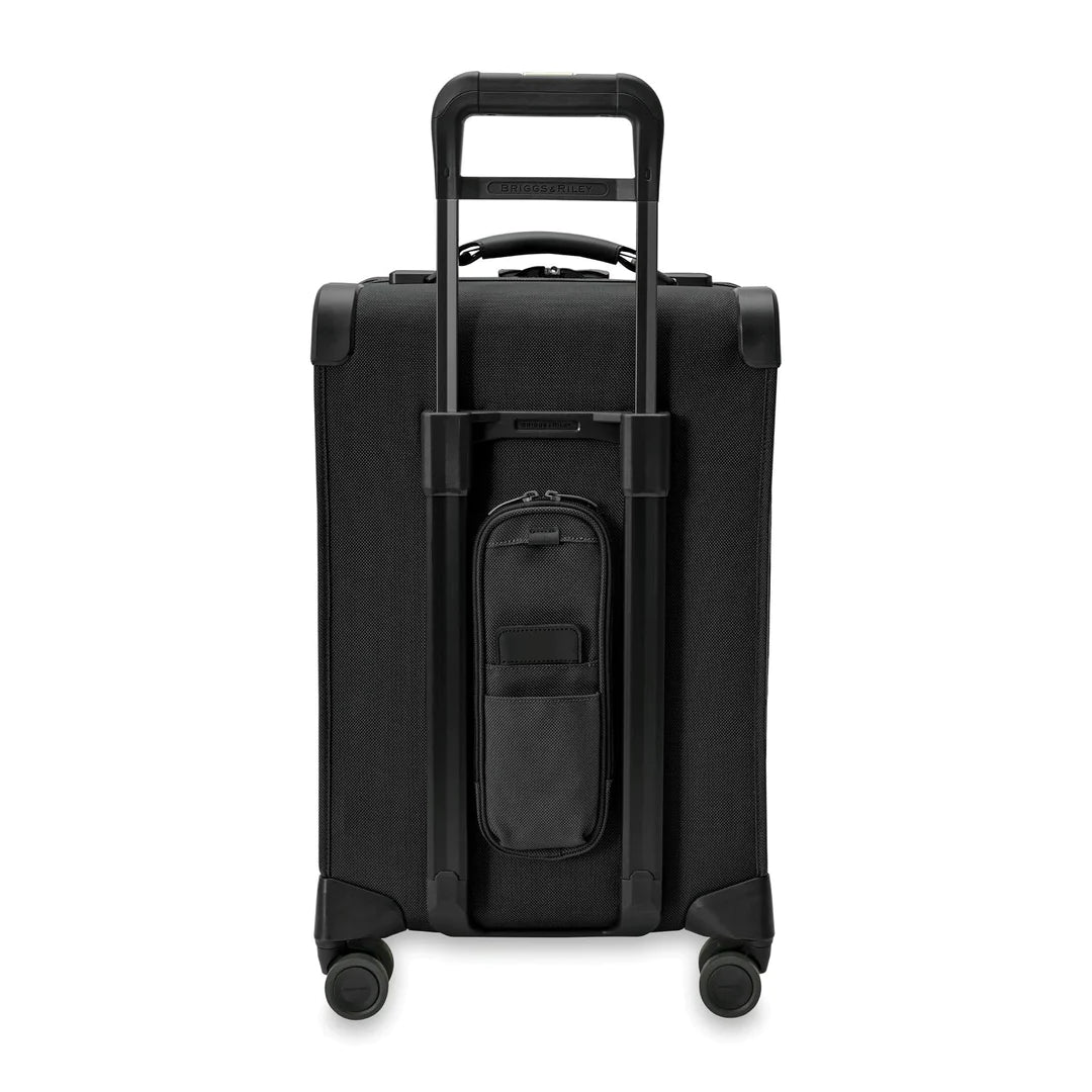 The Briggs & Riley Baseline Essential 22 Carry-On Expandable Spinner in black features a retractable handle, four wheels, a front pocket, garment folder for organized packing, and a small removable pouch below the handle for travel convenience and mobility.