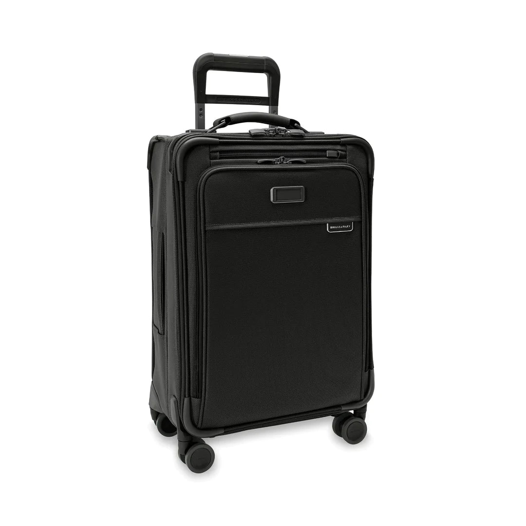 The Briggs & Riley Baseline Essential 22 Carry-On Expandable Spinner in black is a compact suitcase with a telescopic handle, four wheels, and multiple zippered compartments. It includes a garment folder for organized packing, ideal for your travel needs.