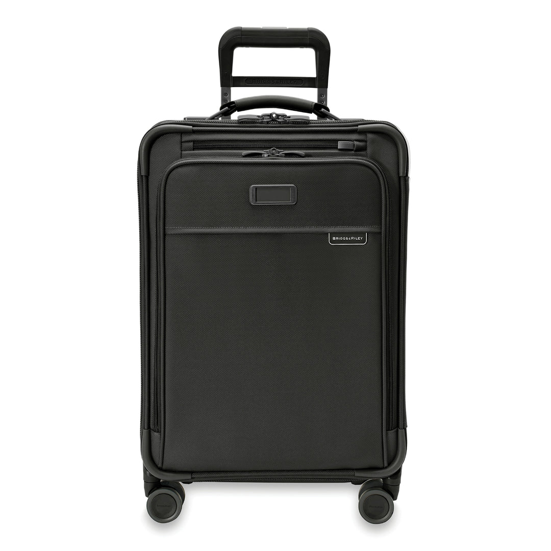 The Briggs & Riley Baseline Essential 22 Carry-On Expandable Spinner in black is a compact suitcase with four wheels, a retractable handle, front zippered pocket, nameplate above it, and includes an internal garment folder for travel convenience.