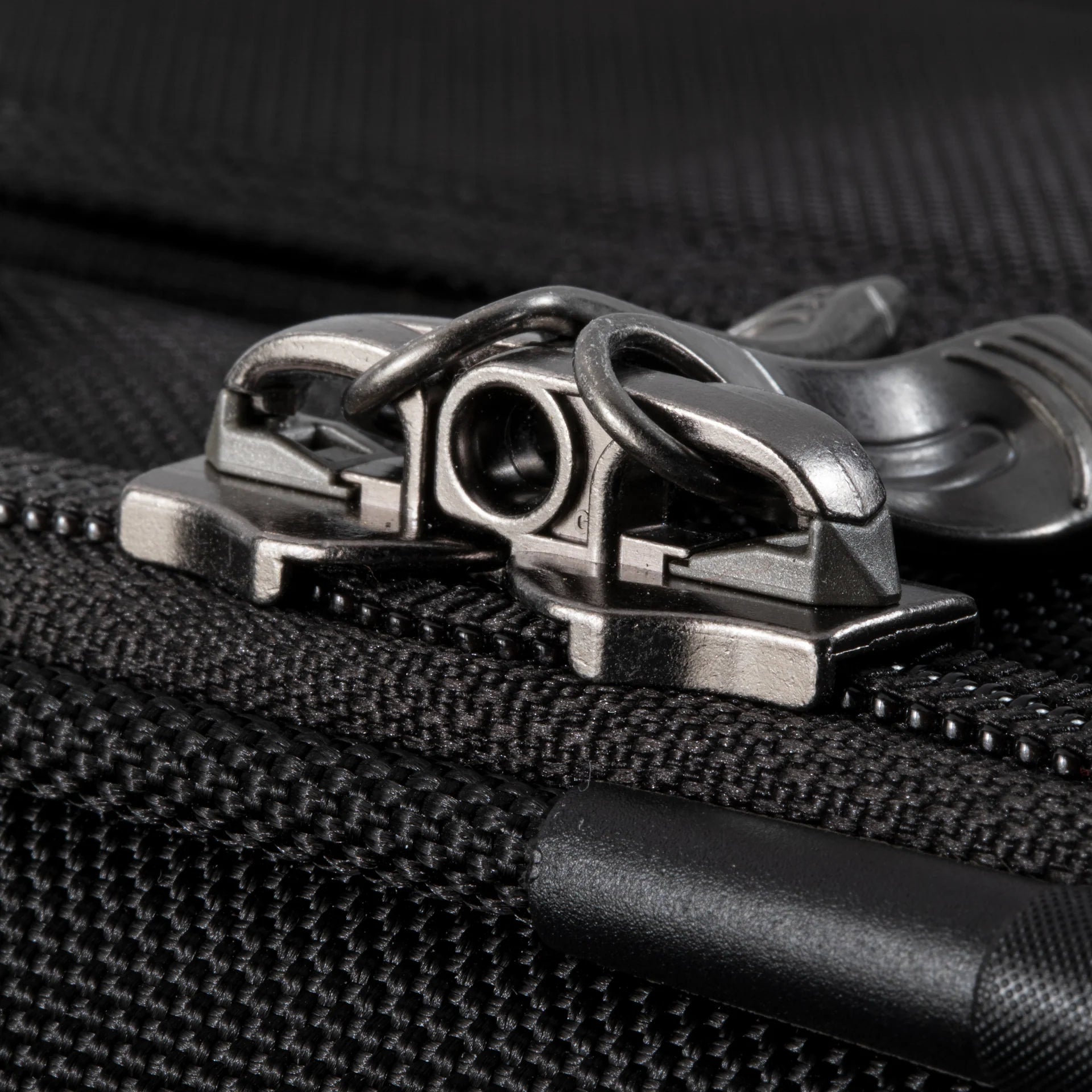 Ricardo Flight Essentials Softside Carry-On - Black, Close-up of a zipper with interlocking metal pullers, designed for a TSA lock.